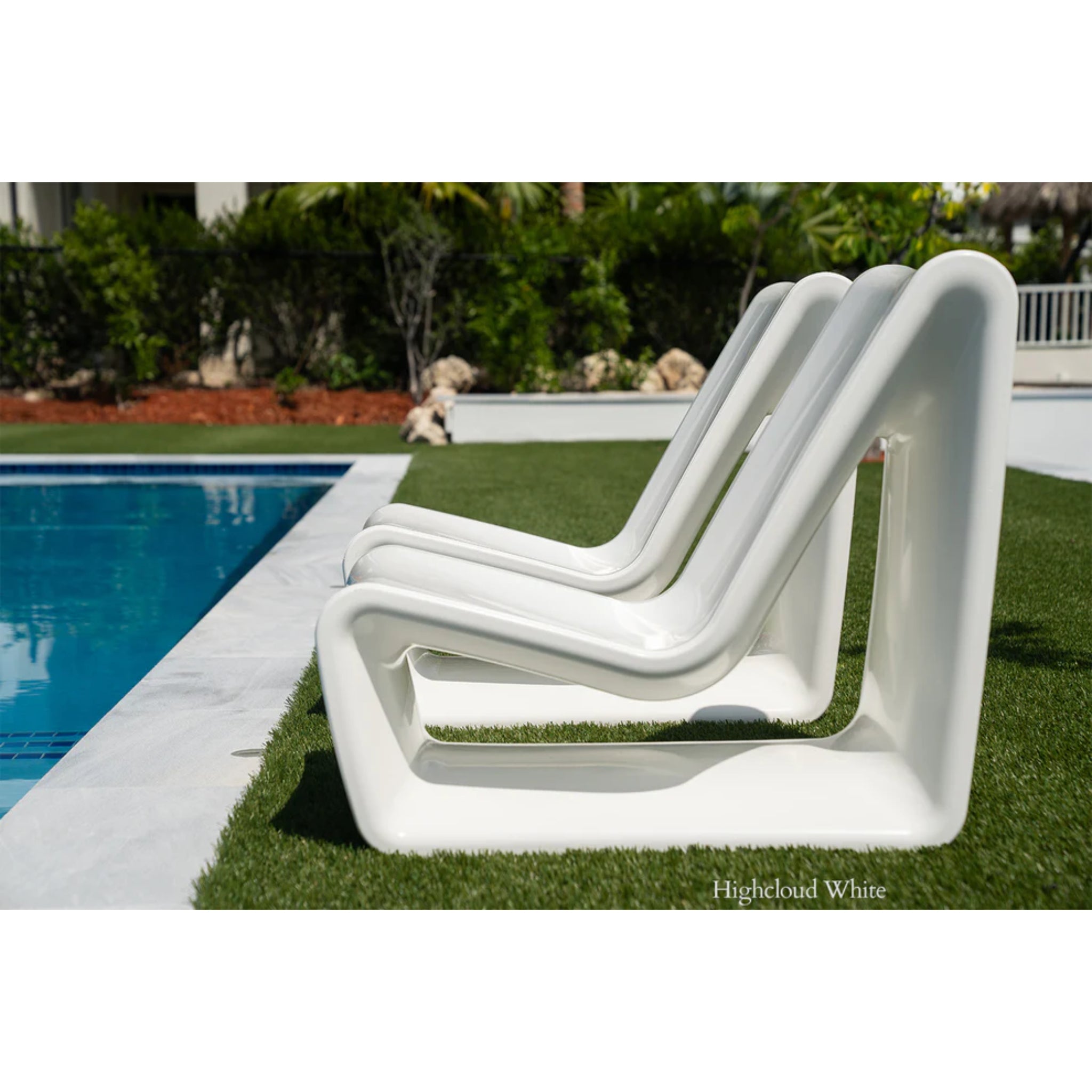 Luxury white outdoor lounge chair positioned on a baja shelf beside a resort-style swimming pool