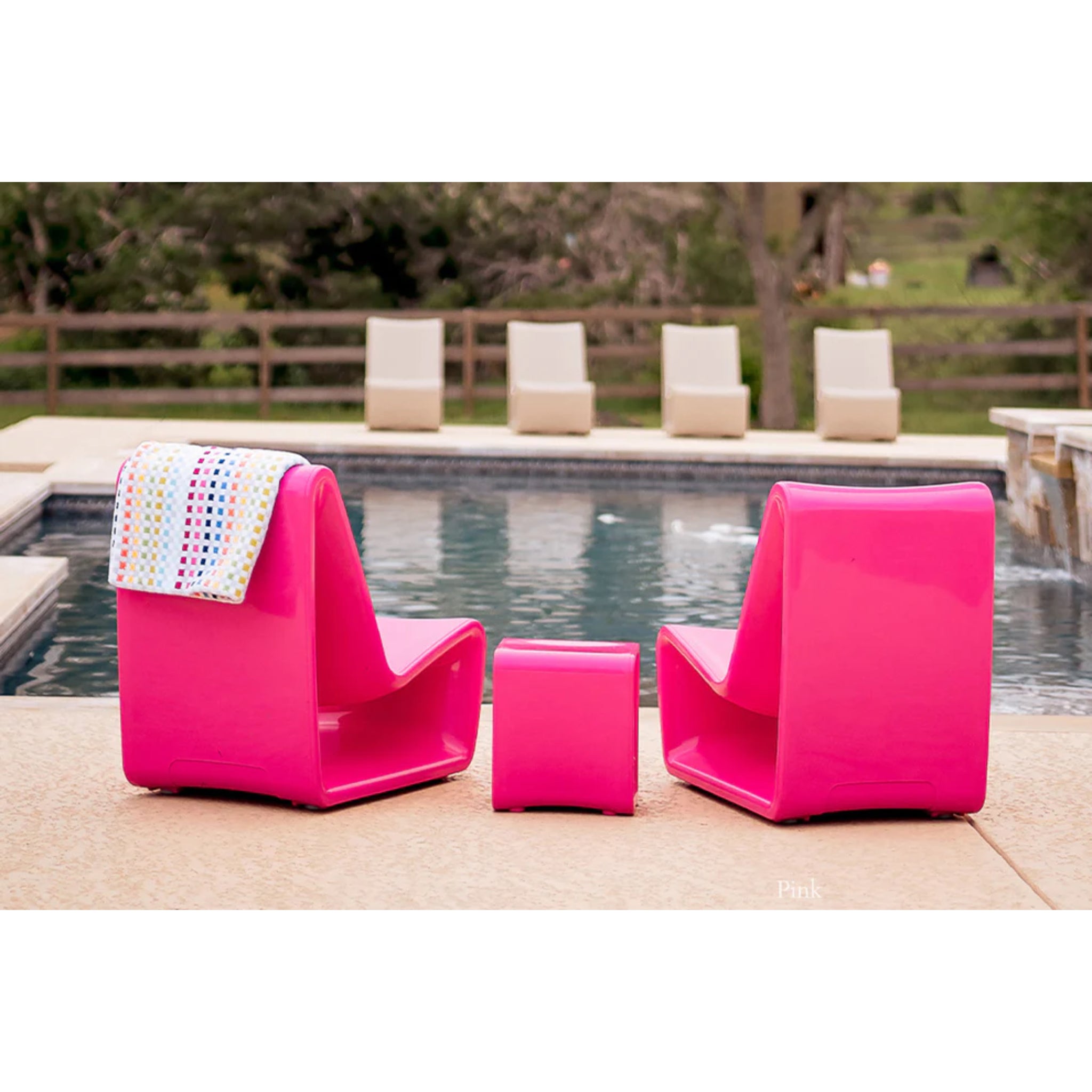 Pink outdoor side table adding vibrant style to a luxury poolside seating arrangement