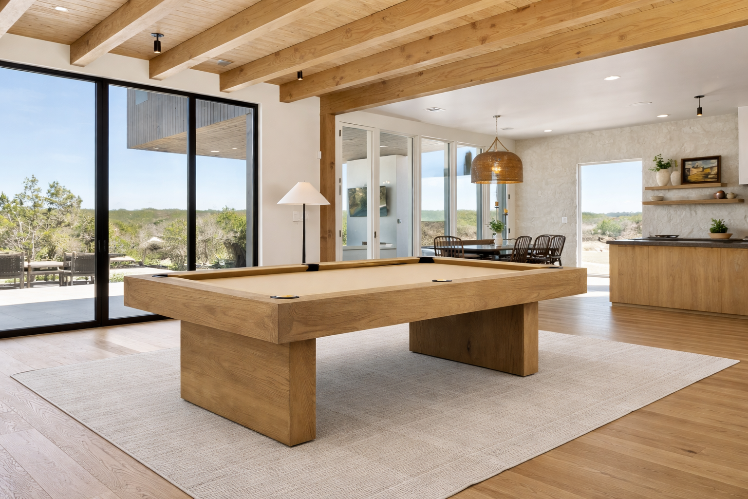 Wood pool table in a modern living room with large windows and kitchen.