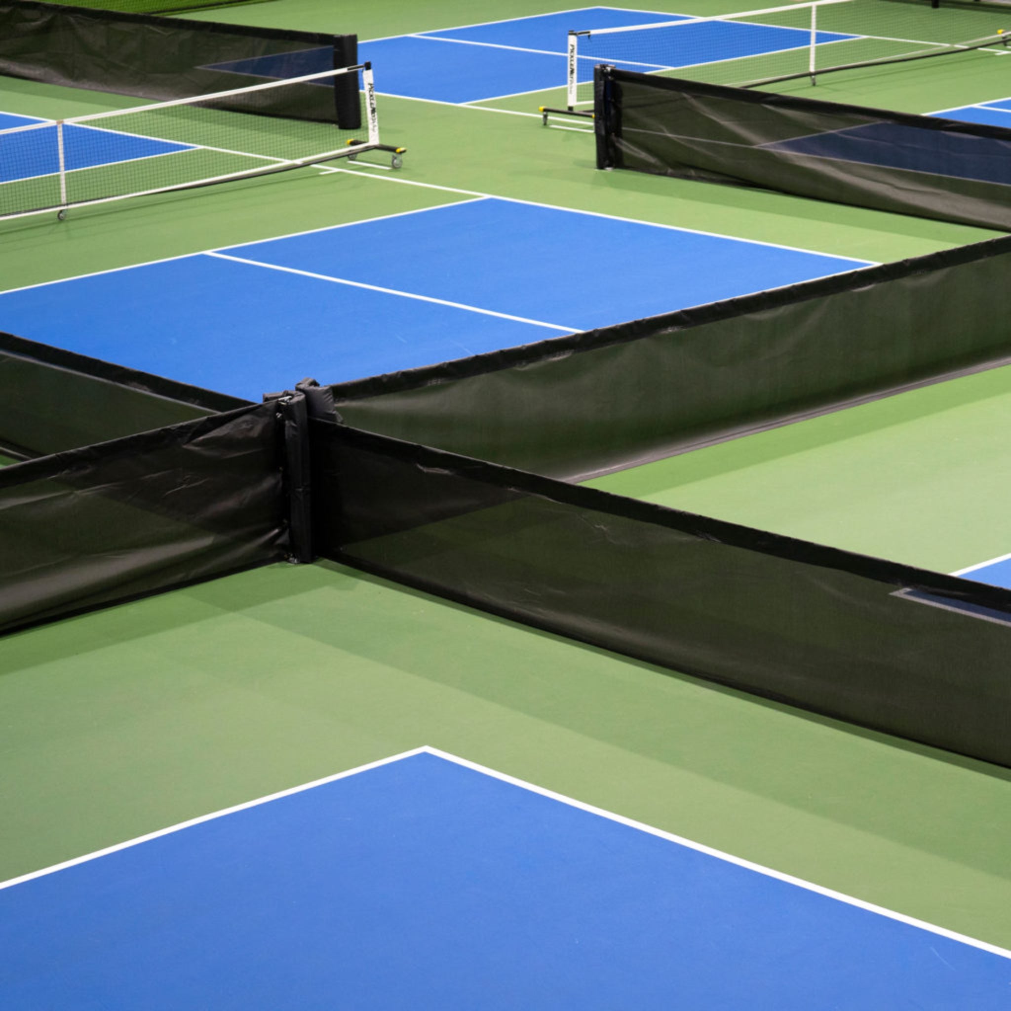 Steel baseplate court divider system anchored to concrete