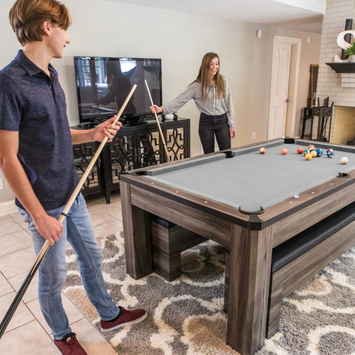 Atomic Hampton 3-in-1 billiard table in gray wood grain finish with players enjoying a game of pool