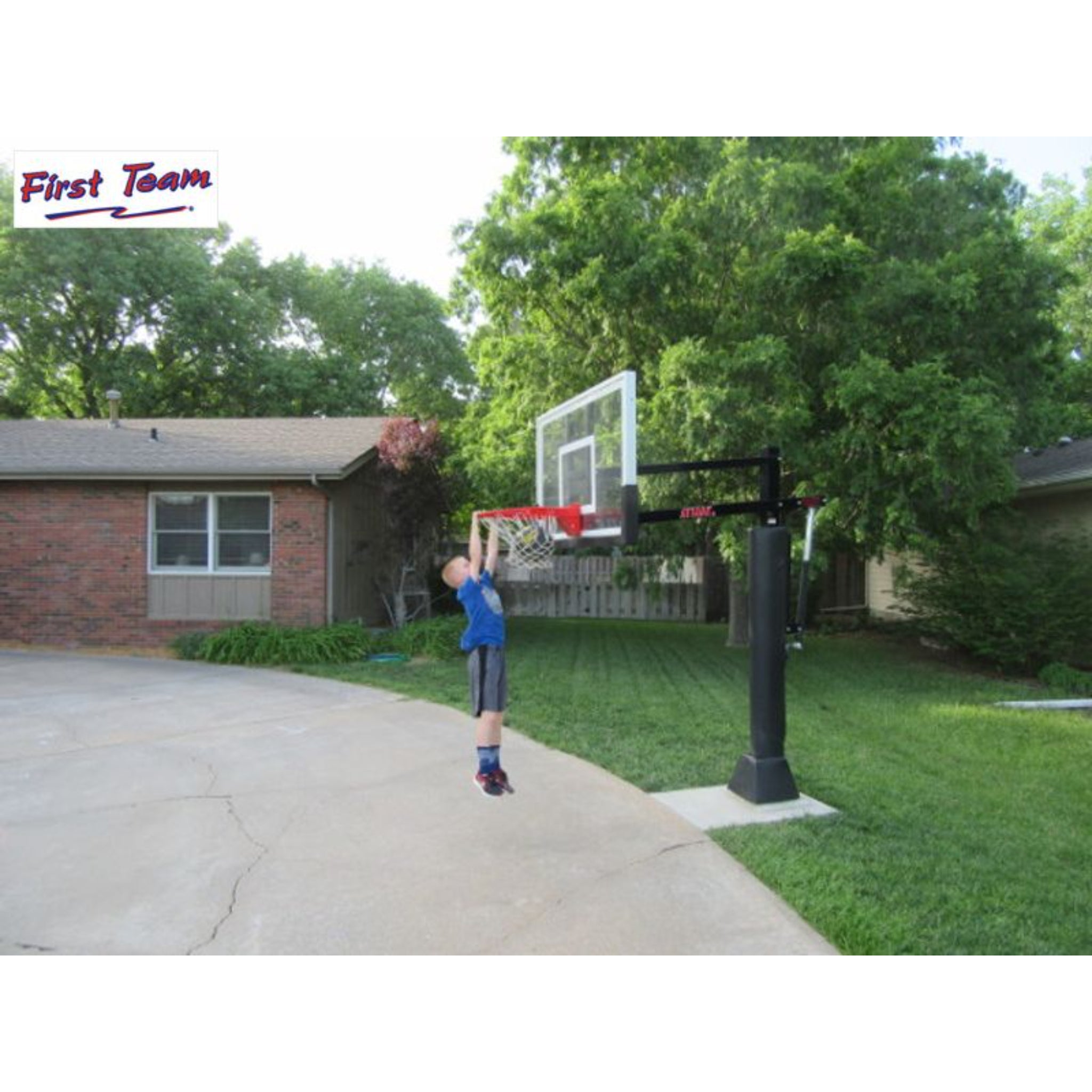 Kid playing basketball on a residential court with the First Team Attack adjustable basketball hoop