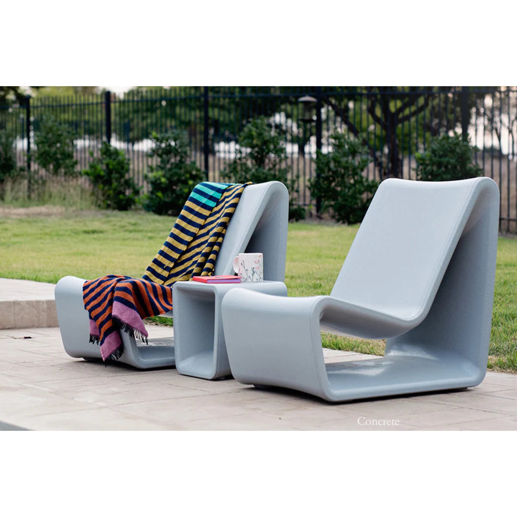 Tupelo Concrete gray outdoor loop side table paired with luxury in-pool lounge furniture on patio