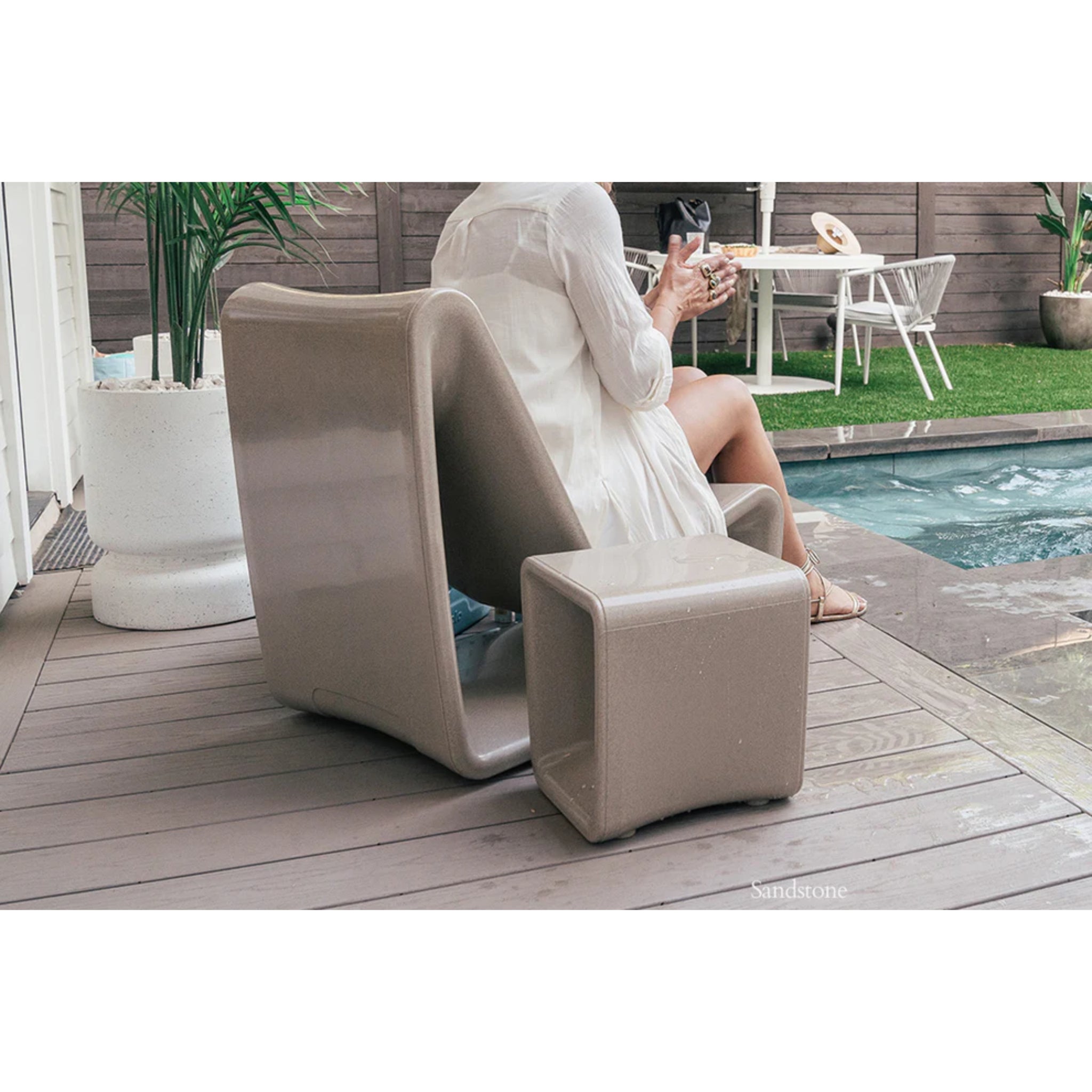 Sandstone outdoor accent table complementing luxury pool furniture on a residential tanning ledge