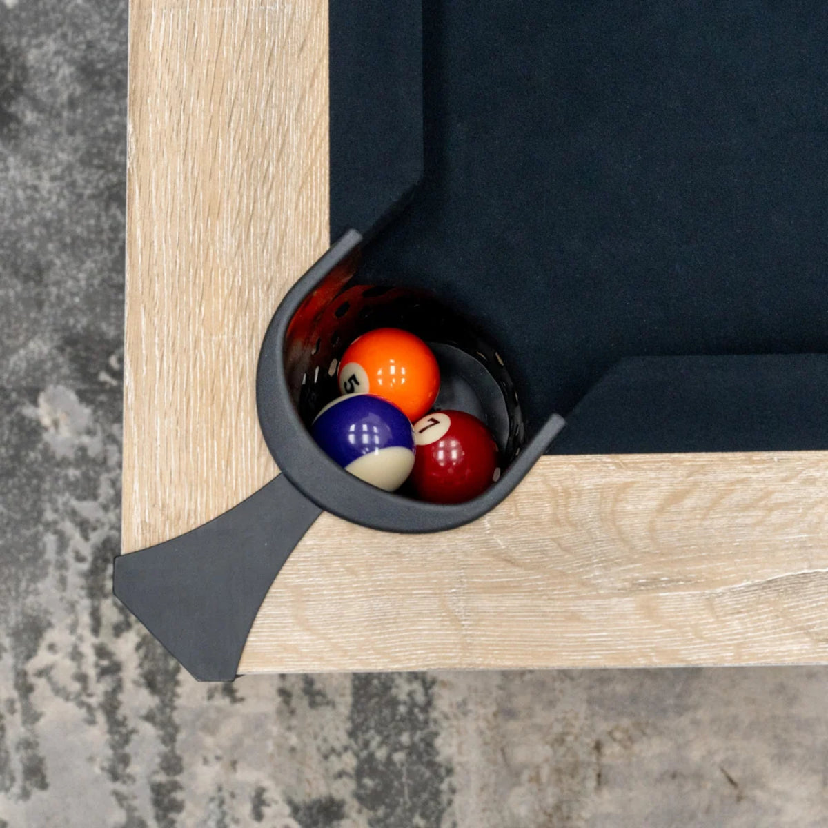 Close-up of black billiard cloth and corner pocket on the Atomic Hampton white oak game table