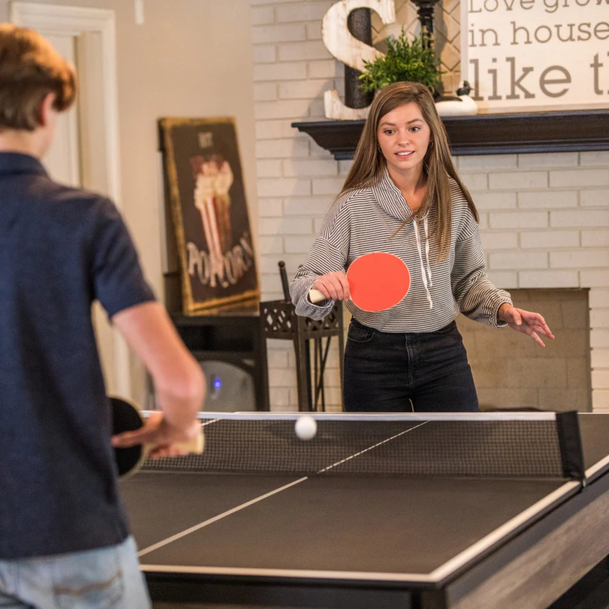 Two people playing table tennis on the Atomic Hampton 7-foot multifunctional game table