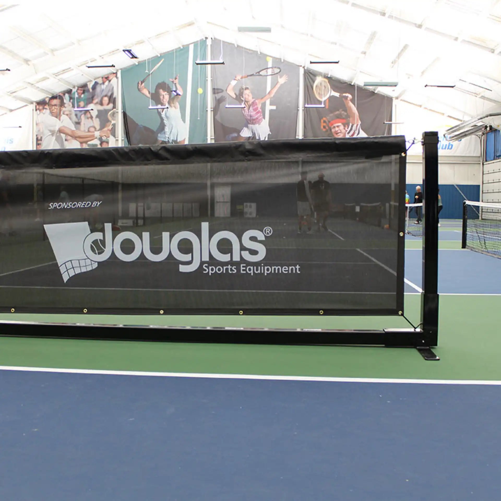 Douglas pickleball court divider barrier installed in an indoor sports facility with black mesh panel and freestanding steel frame.