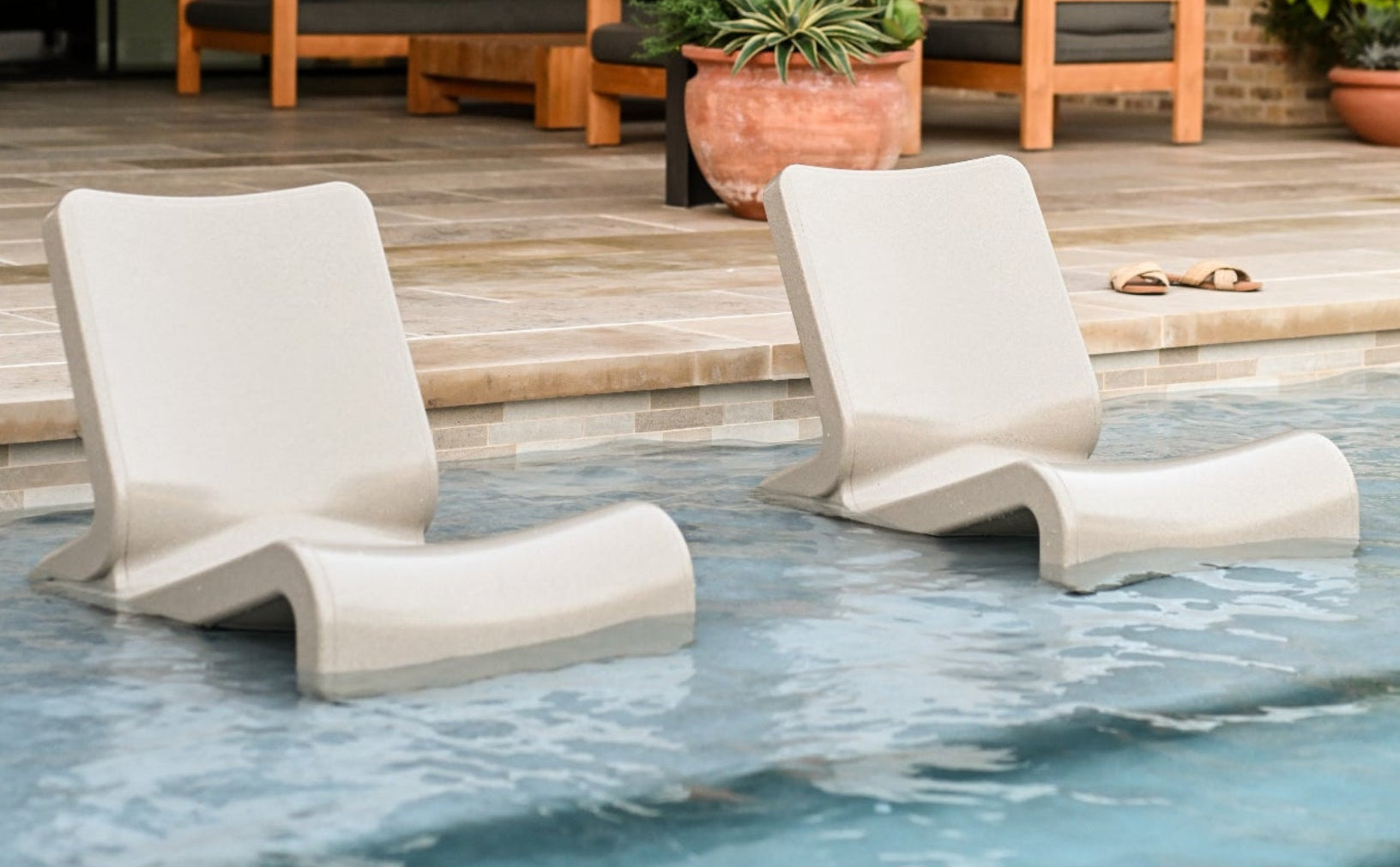 Two  Line Lounge Chairs Sandstone color by Tupelo Goods positioned on a shallow pool tanning ledge as baja pool loungers, designed for comfortable in-pool relaxation on a sun shelf; SKU: 8900-740