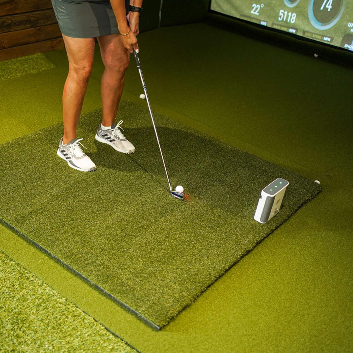 Golfer practicing inside a home golf simulator on a 5' x 5' Real Feel golf practice mat, with the Country Club First Cut turf providing realistic fairway resistance, natural strike feedback, and a comfortable hitting surface for indoor golf practice.