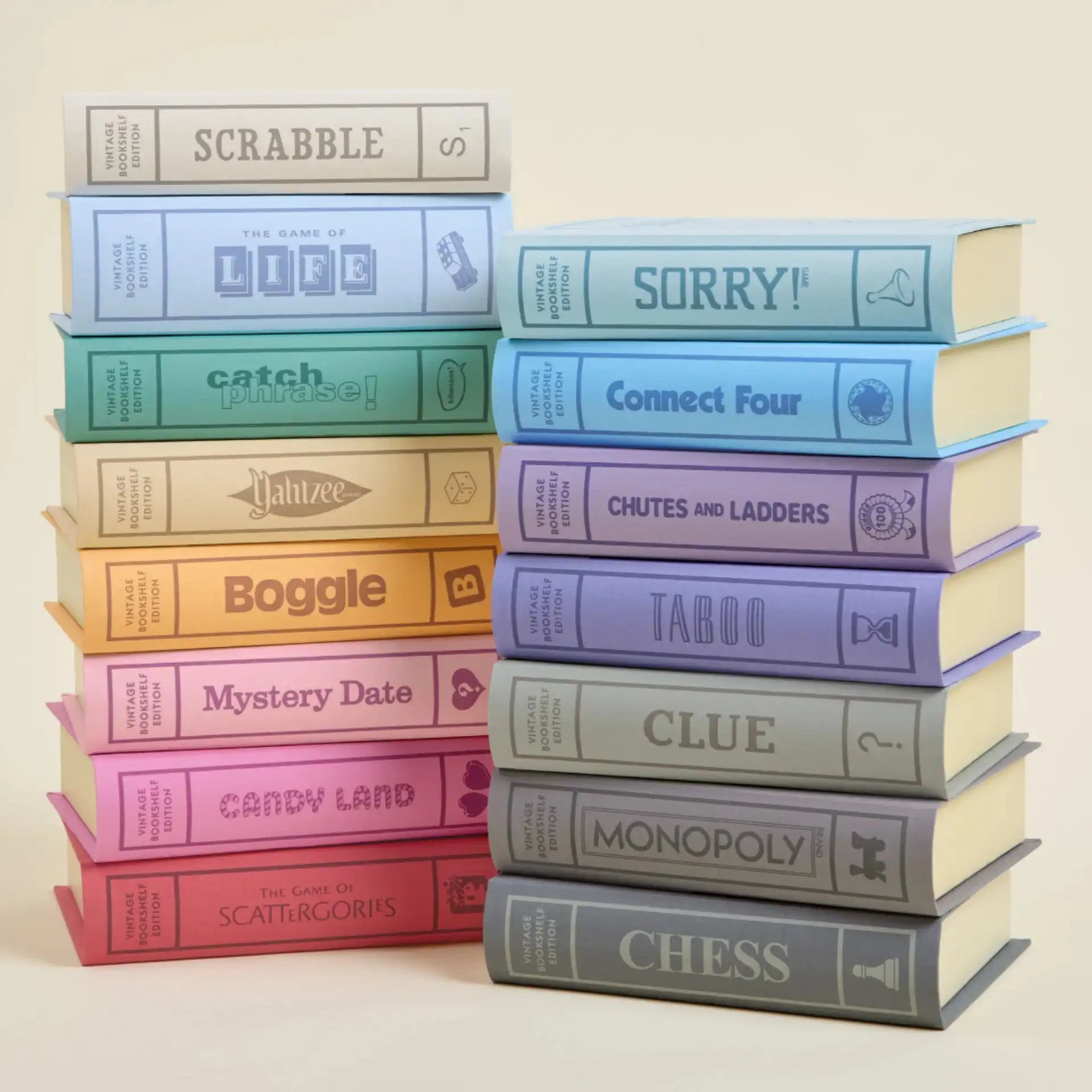 Vintage board games featuring 15 decorative board game books stacked in two towers, with the left tower featuring Scrabble, The Game of Life, Catch Phrase, Yahtzee, Boggle, Mystery Date, Candy Land, and Scattergories, and the right tower featuring Sorry, Connect Four, Chutes and Ladders, Taboo, Clue, Monopoly, and Chess.